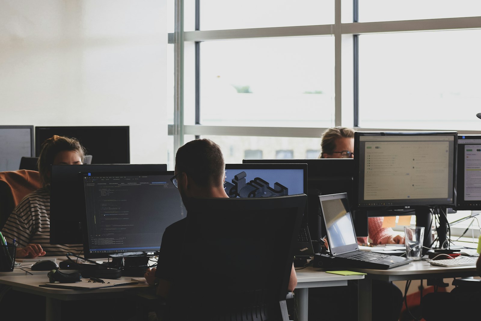 Pessoas trabalhando em computadores em um escritório.